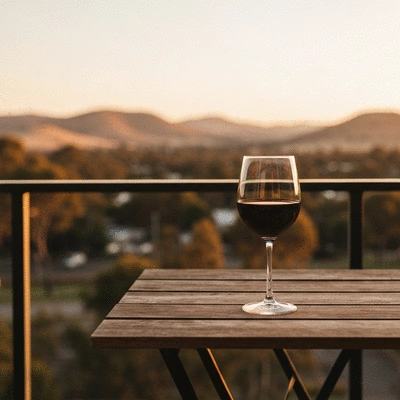Glass of red wine on a wooden table overlooking rolling hills at sunset